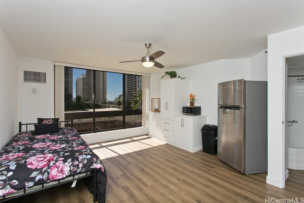 bedroom featuring ceiling fan, stainless steel refrigerator, and hardwood / wood-style floors