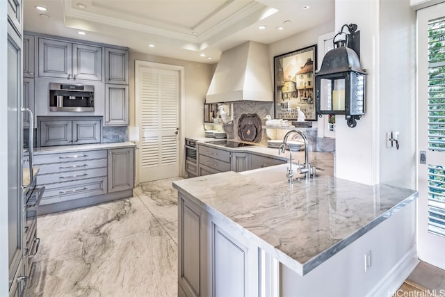 kitchen featuring kitchen peninsula, decorative backsplash, a tray ceiling, and gray cabinetry