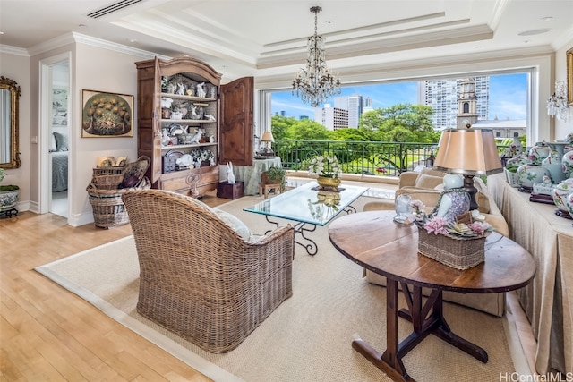 living area with a healthy amount of sunlight, crown molding, light hardwood / wood-style floors, and a raised ceiling