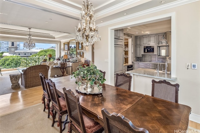 dining area with ornamental molding, light wood-type flooring, and a raised ceiling