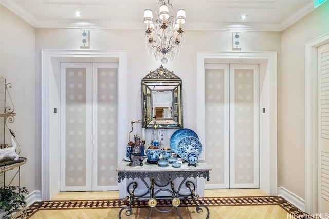 foyer entrance with a notable chandelier, wood-type flooring, and ornamental molding