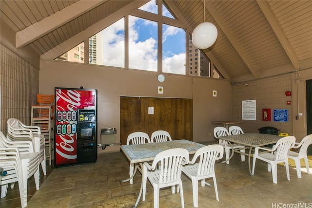 dining area featuring beam ceiling, wood ceiling, high vaulted ceiling, and wood walls