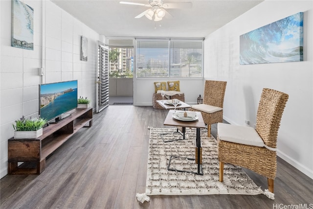 living area with dark hardwood / wood-style floors, tile walls, and ceiling fan