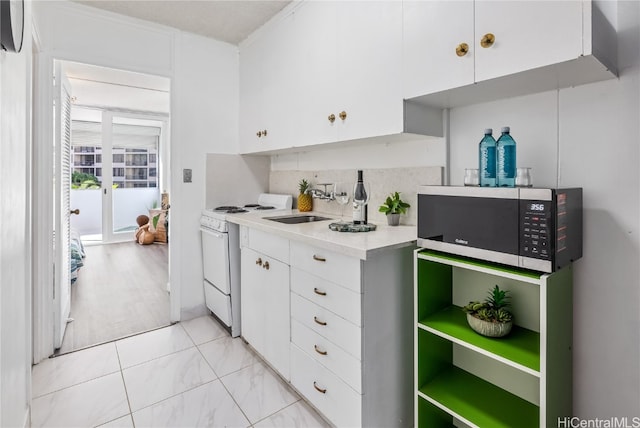 kitchen featuring sink, tasteful backsplash, white range oven, and white cabinets