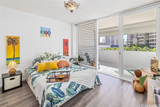 bedroom featuring a textured ceiling, access to exterior, and hardwood / wood-style flooring