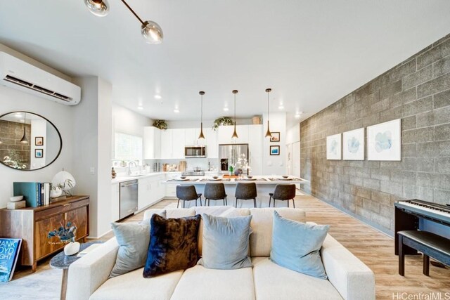 living room featuring sink, light hardwood / wood-style flooring, and an AC wall unit