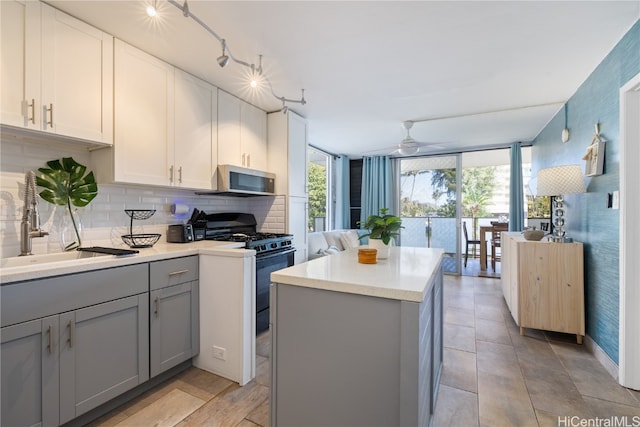 kitchen featuring white cabinets, backsplash, black gas stove, gray cabinetry, and a center island