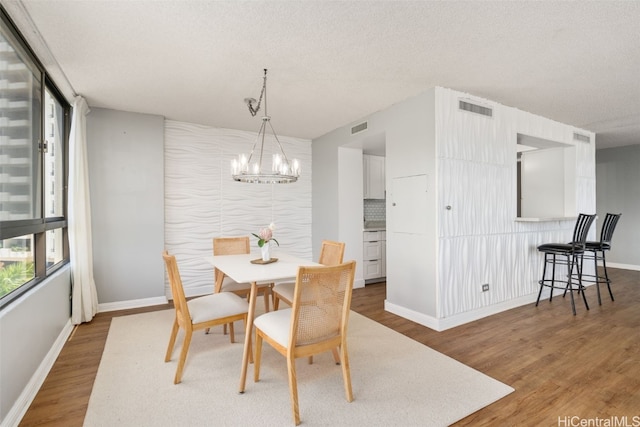 dining space featuring a textured ceiling, a notable chandelier, and hardwood / wood-style flooring