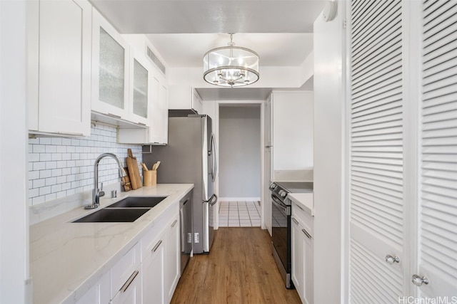 kitchen featuring white cabinetry, black / electric stove, light wood-type flooring, pendant lighting, and sink