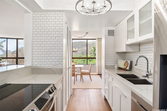 6770 Hawaii Kai Dr Unit 302, Honolulu, HI 96825 - kitchen featuring a sink, a chandelier, stainless steel appliances, light wood-type flooring, and light stone counters