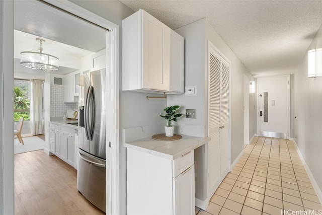 kitchen featuring white cabinetry, a notable chandelier, stainless steel refrigerator with ice dispenser, and a textured ceiling