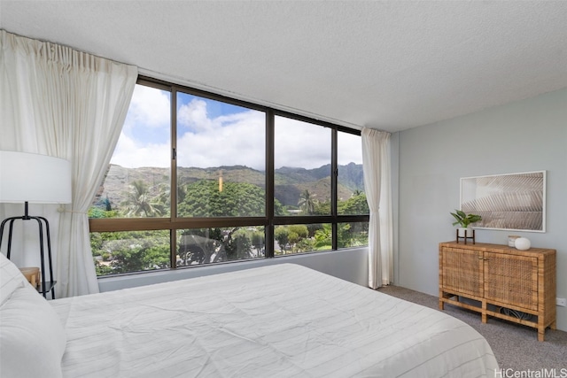 bedroom featuring a textured ceiling, a mountain view, multiple windows, and carpet flooring