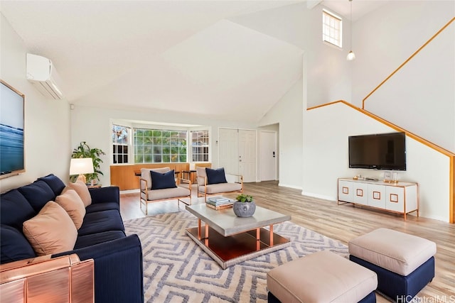 living room featuring a wall mounted air conditioner, a healthy amount of sunlight, high vaulted ceiling, and light hardwood / wood-style floors