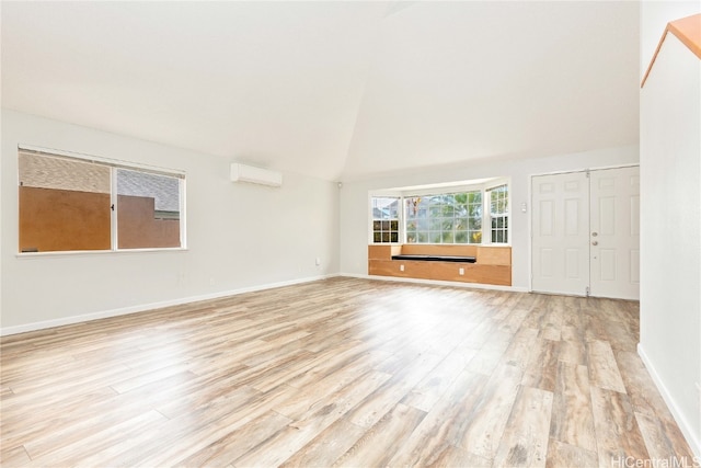 unfurnished living room with vaulted ceiling, an AC wall unit, and light hardwood / wood-style flooring