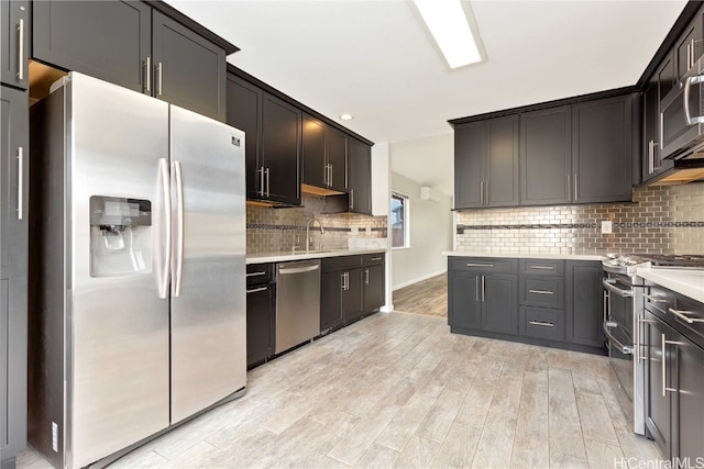 kitchen with light hardwood / wood-style floors, stainless steel appliances, sink, and backsplash