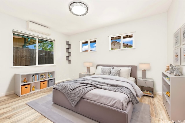 bedroom featuring light hardwood / wood-style floors and an AC wall unit