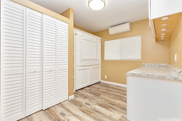 kitchen with a wall mounted AC, light hardwood / wood-style flooring, and white cabinets