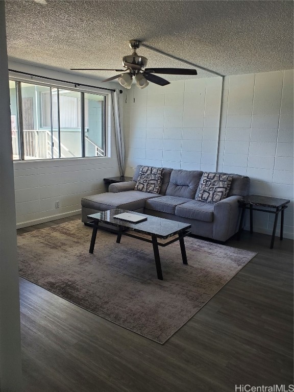 living room featuring a textured ceiling, dark wood-type flooring, and ceiling fan