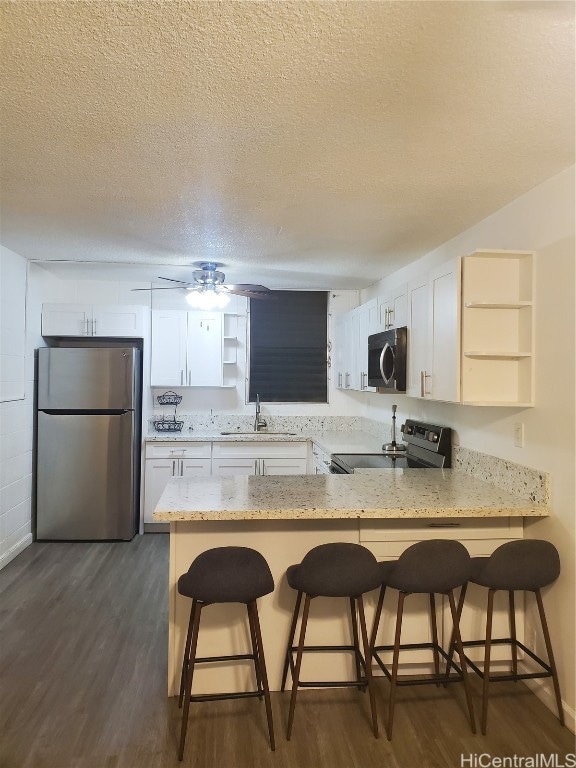 kitchen with kitchen peninsula, white cabinets, stainless steel appliances, and a breakfast bar