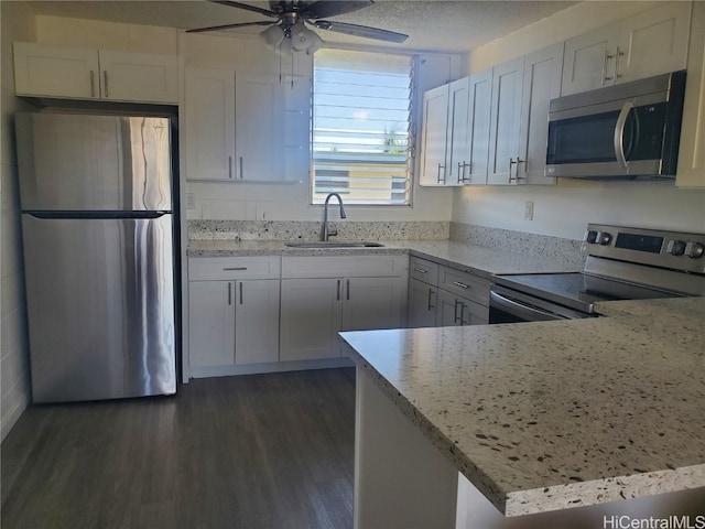 kitchen with a textured ceiling, kitchen peninsula, white cabinetry, stainless steel appliances, and dark hardwood / wood-style floors