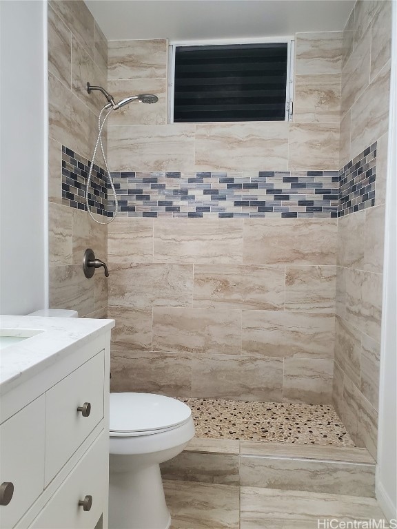 bathroom with vanity, a tile shower, and toilet