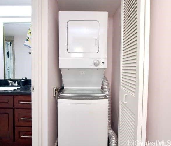 laundry area featuring stacked washer and clothes dryer and sink