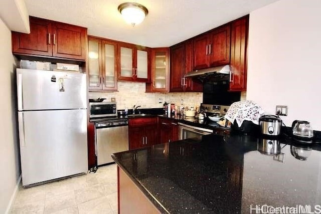 kitchen featuring stainless steel appliances, decorative backsplash, sink, and dark stone counters