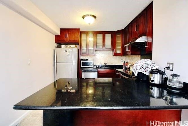 kitchen featuring kitchen peninsula, stainless steel appliances, sink, and backsplash