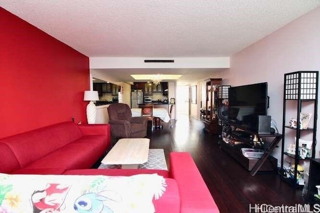 living room with a textured ceiling, a notable chandelier, and hardwood / wood-style flooring