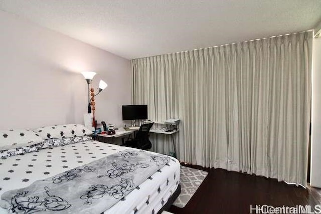 bedroom with a textured ceiling and dark hardwood / wood-style flooring