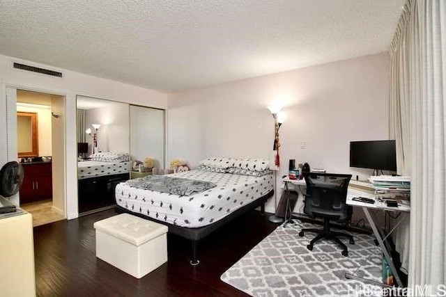 bedroom with a closet, dark wood-type flooring, and a textured ceiling