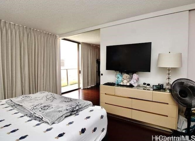 bedroom featuring dark wood-type flooring, expansive windows, and a textured ceiling