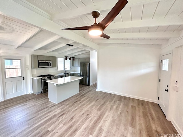 kitchen with vaulted ceiling with beams, stainless steel appliances, and light wood-type flooring