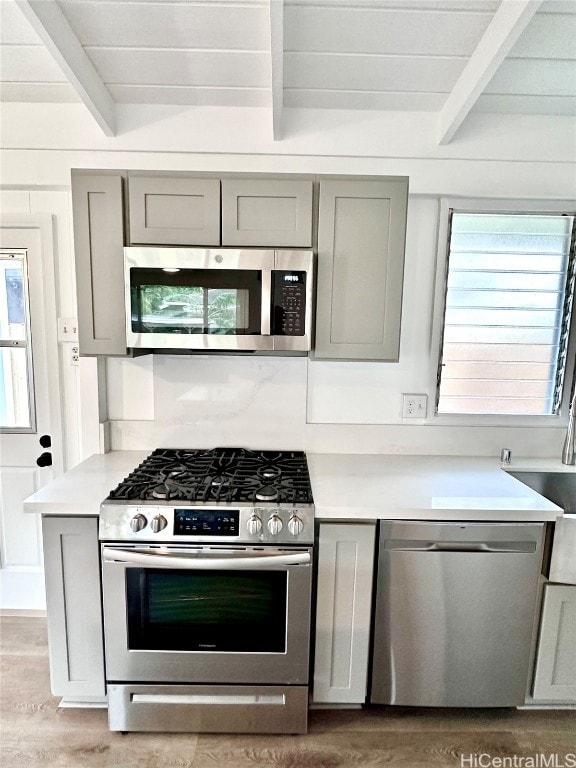 kitchen with beam ceiling, appliances with stainless steel finishes, and a wealth of natural light