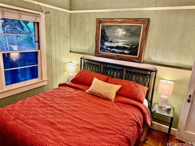 bedroom with ornamental molding, wooden walls, and hardwood / wood-style flooring