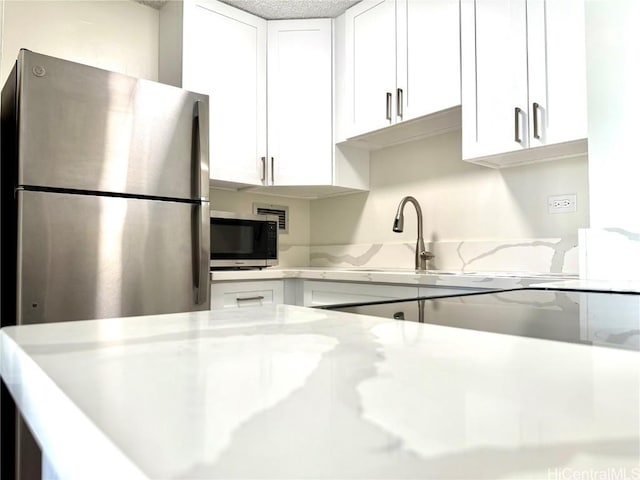 kitchen featuring white cabinets, light stone countertops, and stainless steel appliances