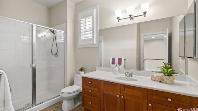 bathroom with tile patterned floors, vanity, toilet, and a shower with shower door