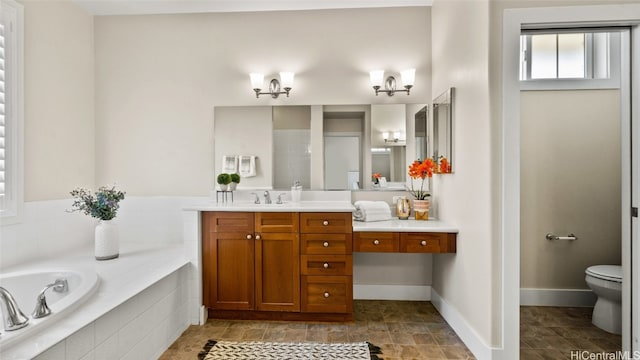 bathroom with tiled bath, vanity, and toilet