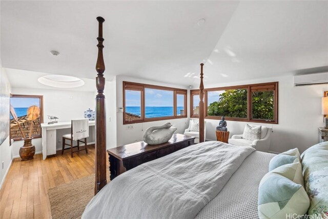 bedroom featuring a water view, hardwood / wood-style floors, and a wall unit AC