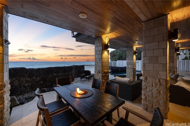 patio terrace at dusk featuring a fire pit and a water view