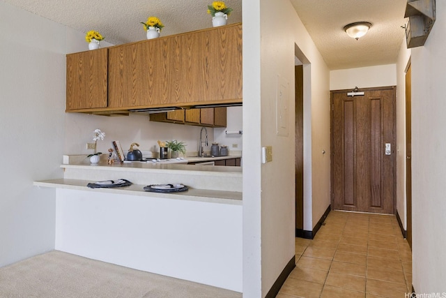 98-501 Koauka Loop Unit A603, Aiea, HI 96701 - kitchen with light countertops, a textured ceiling, a sink, light tile patterned floors, and a peninsula