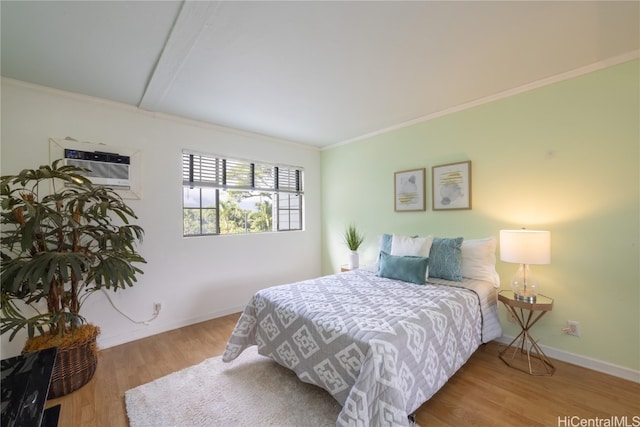 bedroom featuring an AC wall unit, hardwood / wood-style floors, and ornamental molding