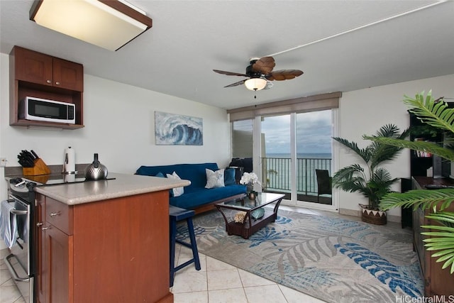 interior space featuring white microwave, ceiling fan, light tile patterned floors, and electric stove