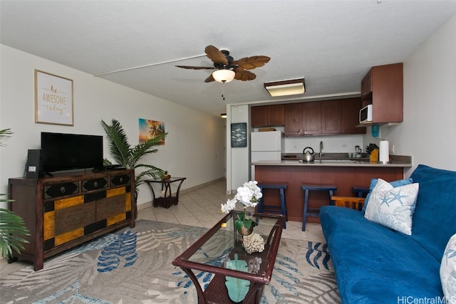 living area with light tile patterned floors, baseboards, and a ceiling fan