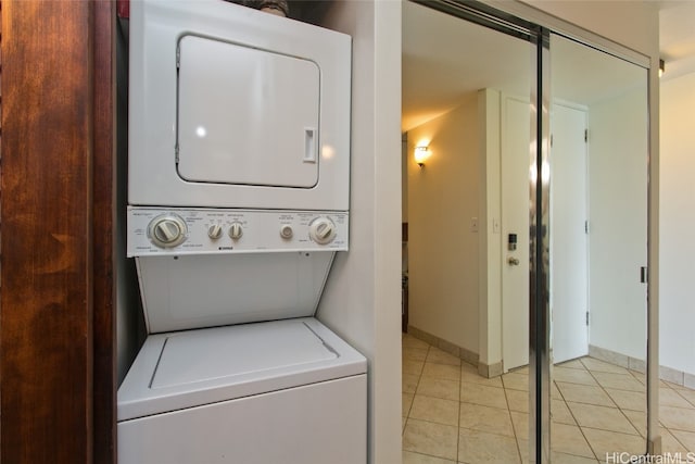 laundry room with baseboards, laundry area, light tile patterned flooring, and stacked washer / drying machine