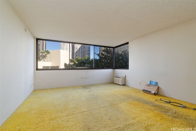 spare room with a textured ceiling, carpet floors, and a wall mounted air conditioner