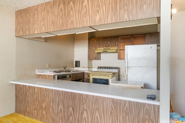 kitchen with sink, kitchen peninsula, a textured ceiling, and white appliances