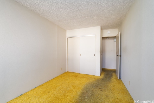 unfurnished bedroom with a textured ceiling, carpet flooring, and a closet