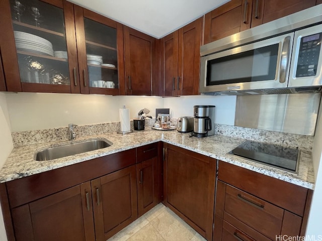 kitchen featuring sink, light stone countertops, and black electric cooktop