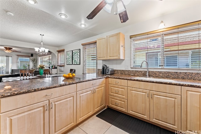 kitchen featuring sink, dark stone counters, pendant lighting, a textured ceiling, and light tile patterned flooring